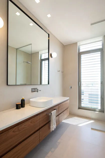Baño moderno con mueble flotante de madera y gran espejo — proyecto Casa AA, por Estudio Junor, en Pilar